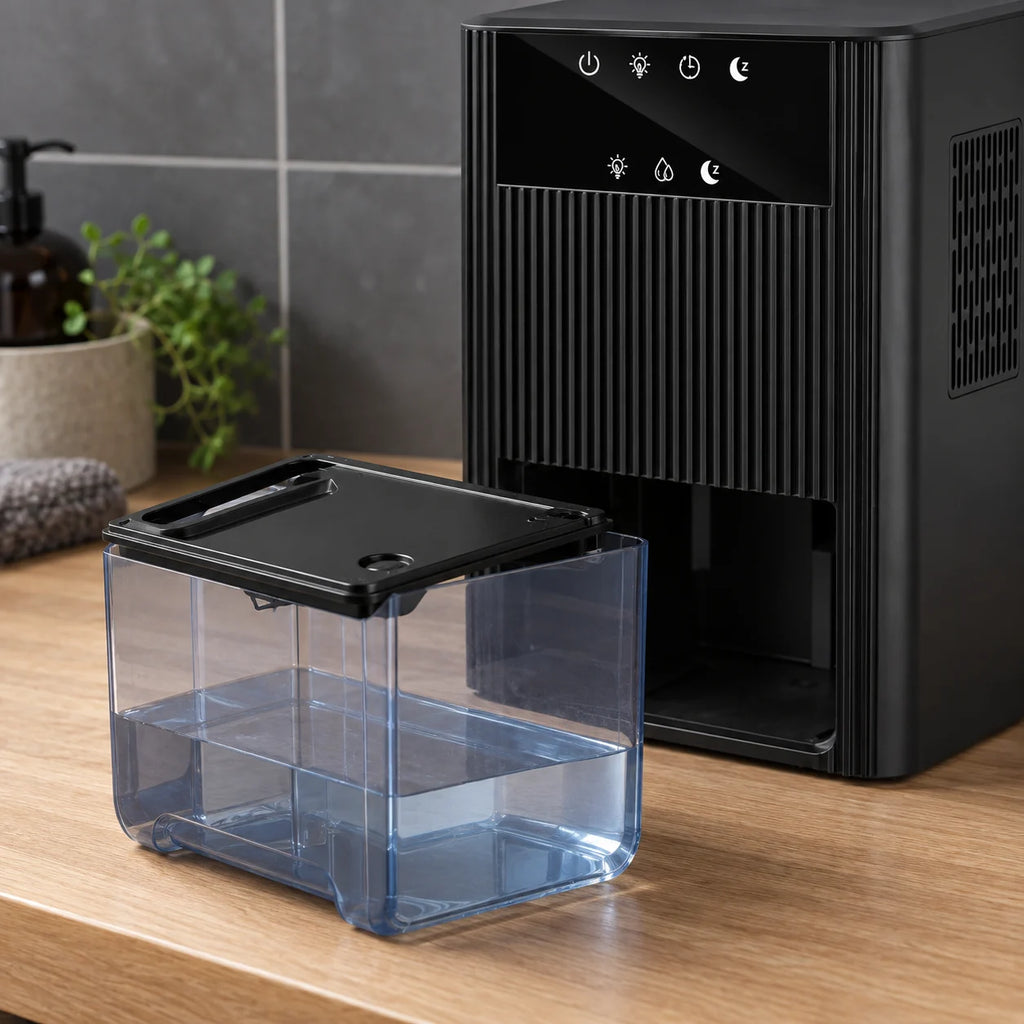 Réservoir transparent de 2,2 litres sorti du déshumidificateur noir, posé sur un plan en chêne